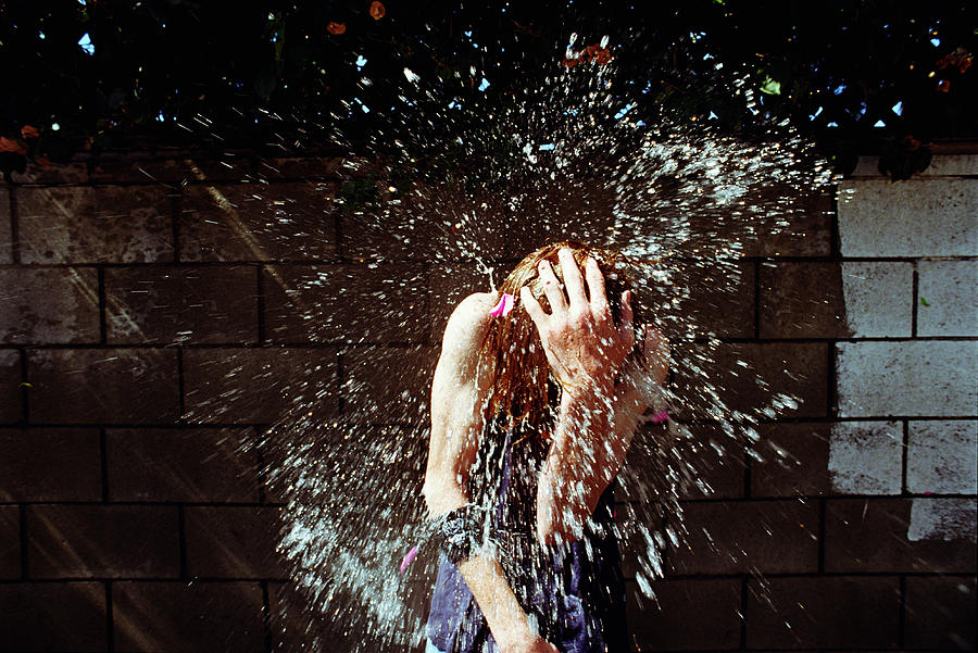 Boy (13-15) being hit with water balloons Photograph by Sean Murphy