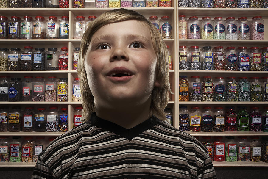 Boy (6-8) in sweetshop, close-up (Digital Composite) Photograph by Tim Macpherson