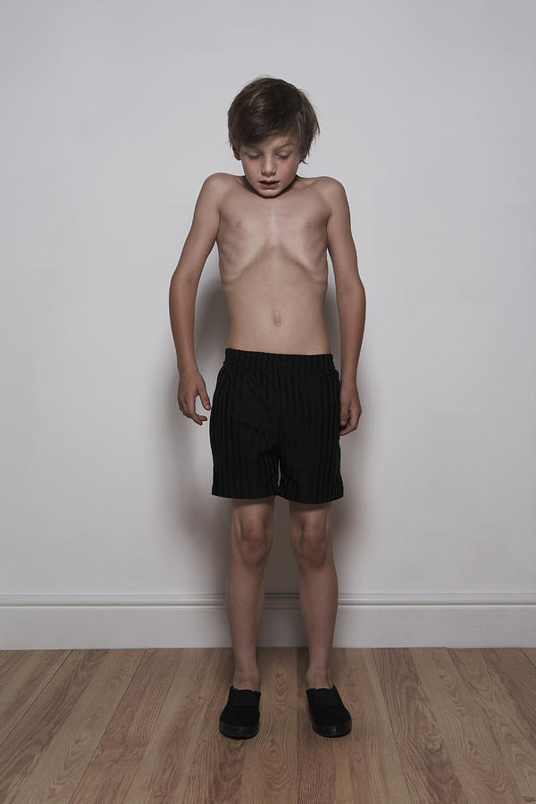 Boy (8-10) standing indoors, taking deep breath Photograph by Tim Macpherson
