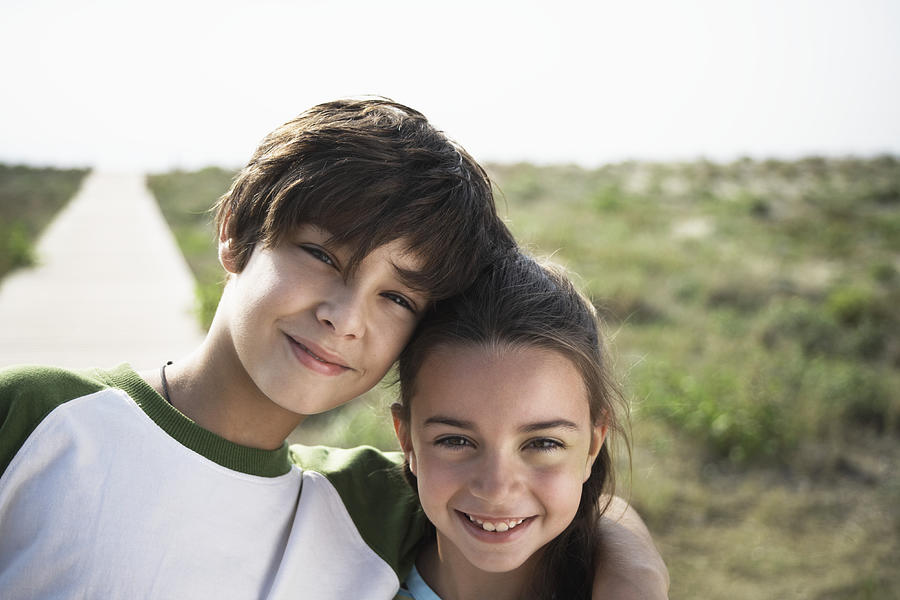 Boy and girl (8-10) on beach boardwalk, close-up, portrait Photograph by Getty Images