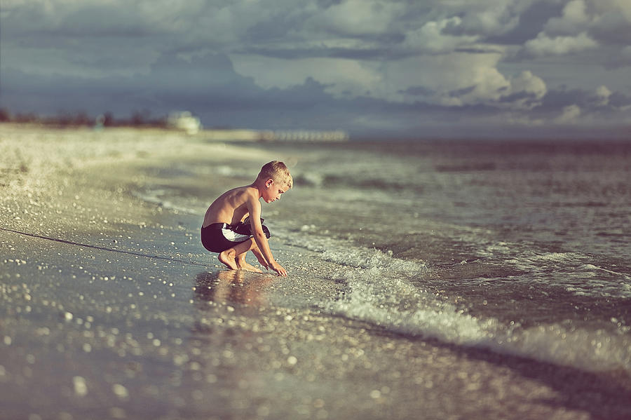 Boy Crouching In Sand Before The Gulf Photograph by Rebecca Nelson