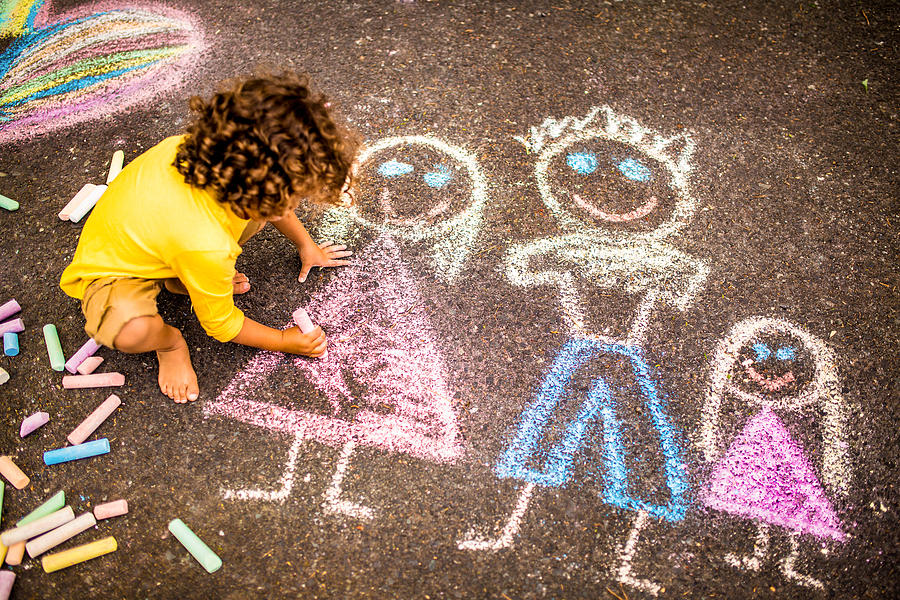 Boy drawing a colourful chalk picture of his family Photograph by Wundervisuals