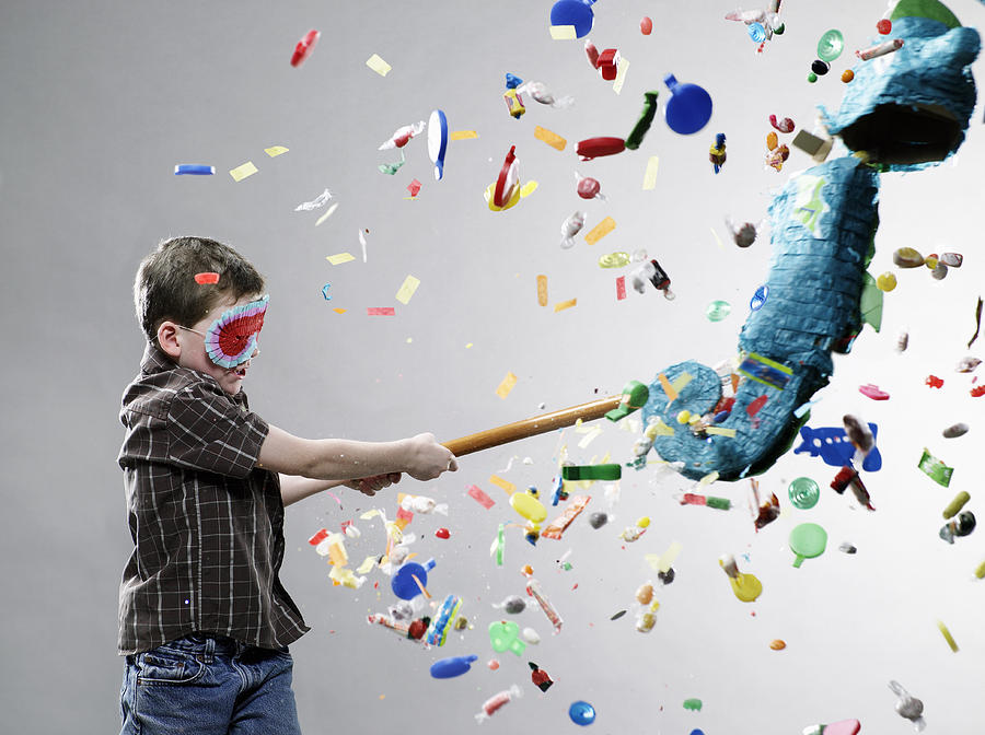 Boy hitting pinata, explosion of candy Photograph by Ryan McVay