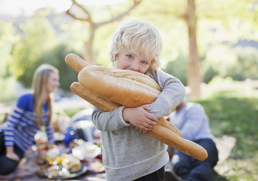 Boy holding loaves of bread outdoors Photograph by Paul Bradbury