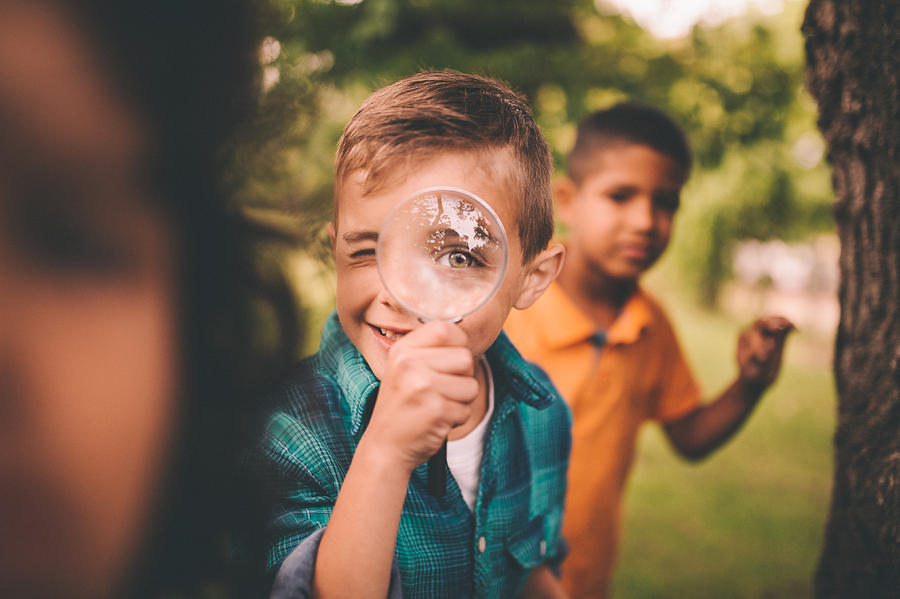 Boy in park holding a magnifying glass to his eye Photograph by Wundervisuals