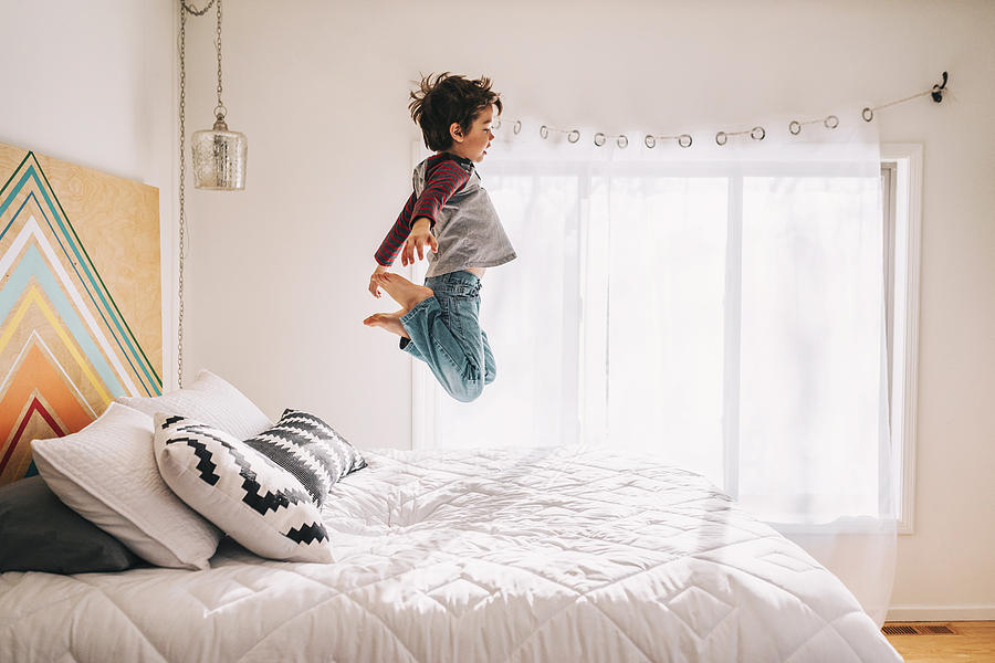 Boy jumping on a bed Photograph by Elizabethsalleebauer