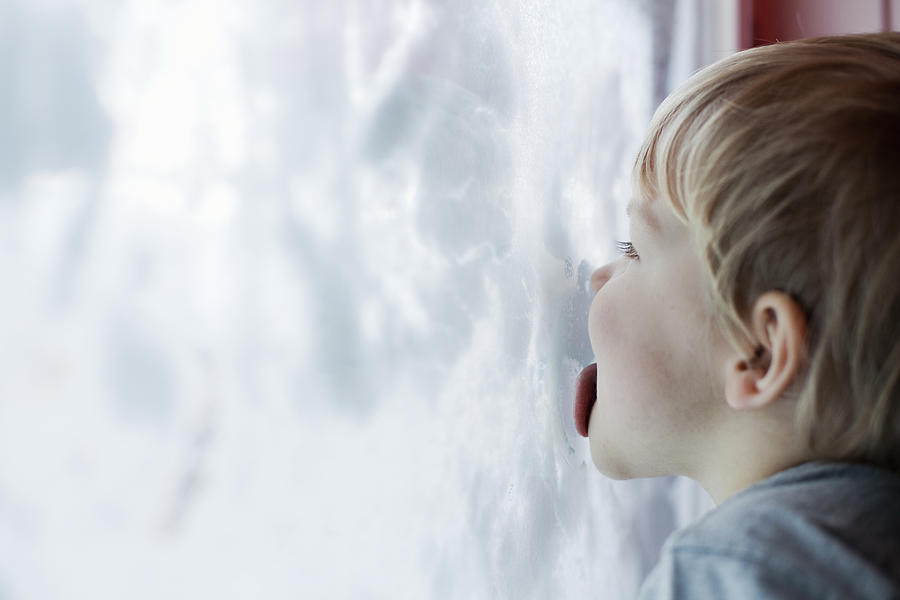 Boy licking inside of snow-covered window Photograph by Tiina & Geir