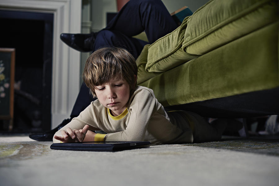 Boy on tablet computer under sofa Photograph by Frank Herholdt