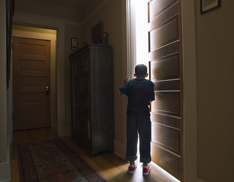 Boy peeking into room with light coming out Photograph by Siri Stafford