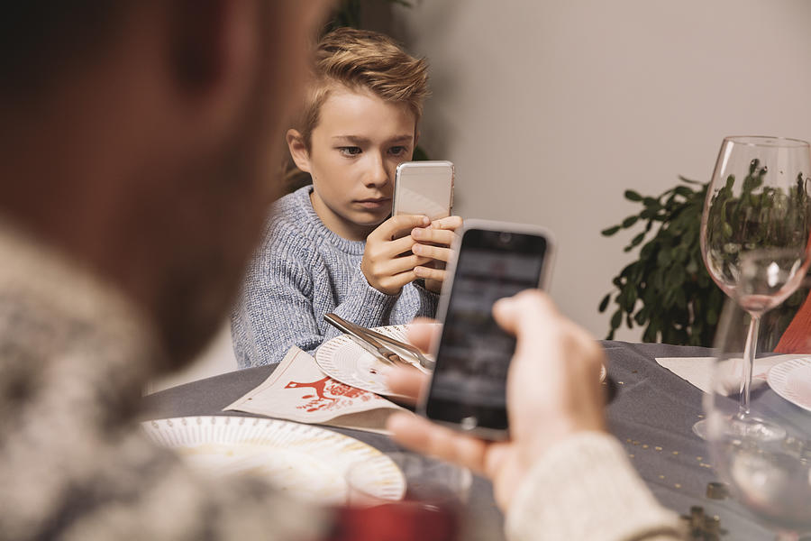 Boy playing with his smartphone after Christmas dinner Photograph by Westend61