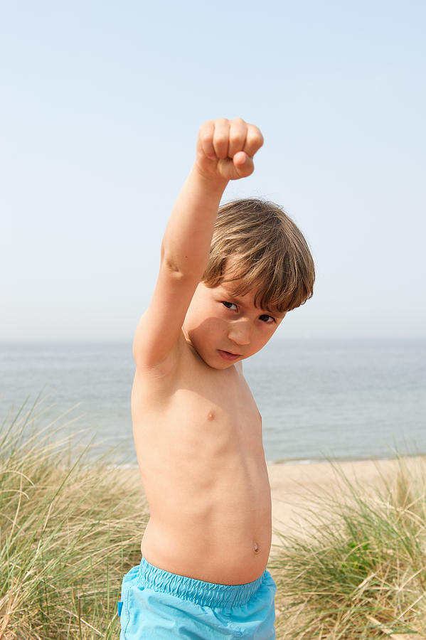 Boy raising his fist on beach Photograph by Cultura RM Exclusive/Benedicte Vanderreydt
