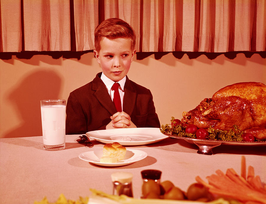 Boy sitting  at table with hands folded for grace prayer, looking at roast turkey. (Photo by H. Armstrong Roberts/Retrofile/Getty Images) Photograph by H. Armstrong Roberts