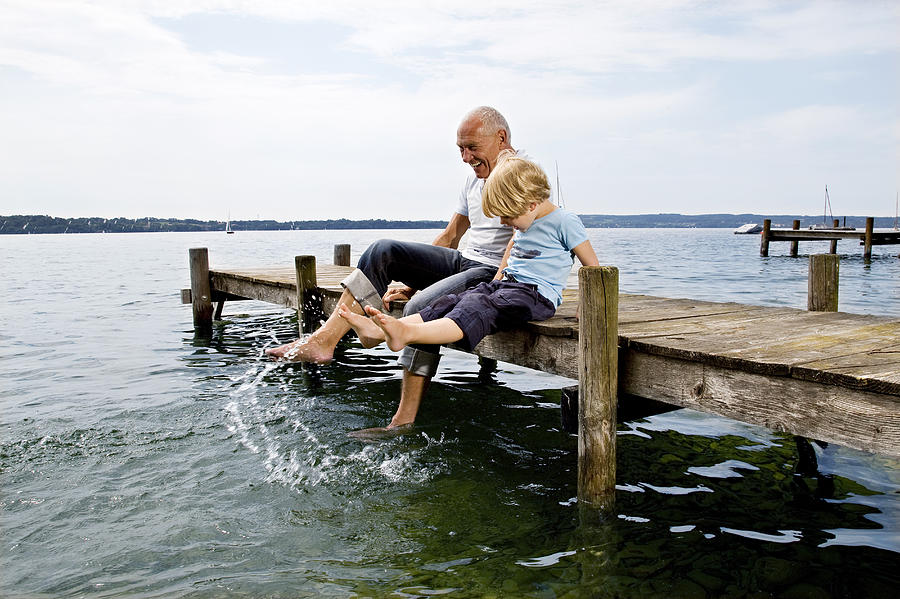 Boy Splashing With Grandfather At Lake Photograph by Henglein and Steets
