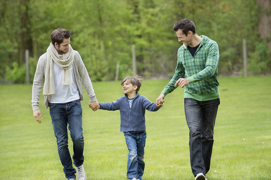 Boy walking with two men in a park Photograph by Eric Audras