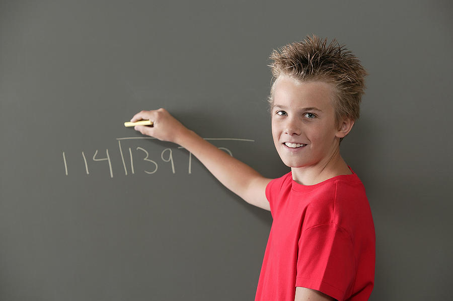 Boy writing on blackboard Photograph by Comstock Images