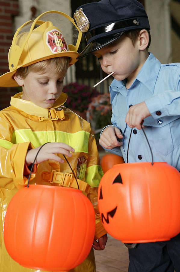 Boys in Halloween costumes eating candy Photograph by Comstock Images