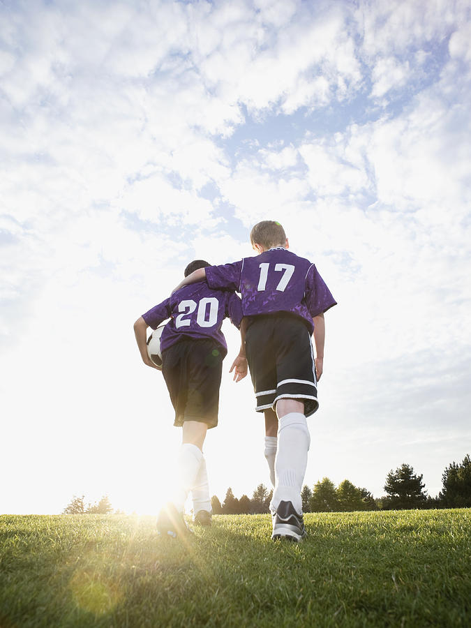 Boys in soccer uniforms walking on field Photograph by Tetra Images - Erik Isakson