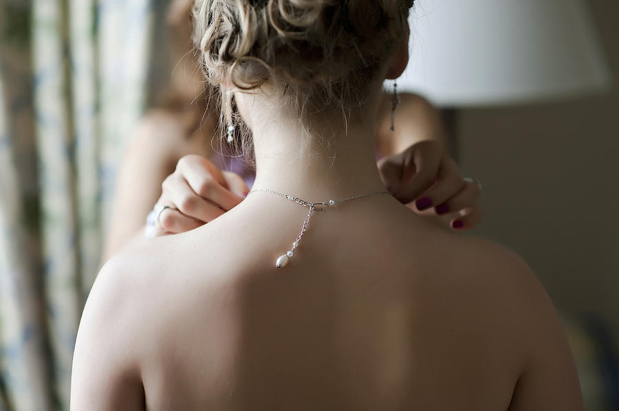 Bridesmaid fixing necklace on bride Photograph by Daniel Sheehan Photographers