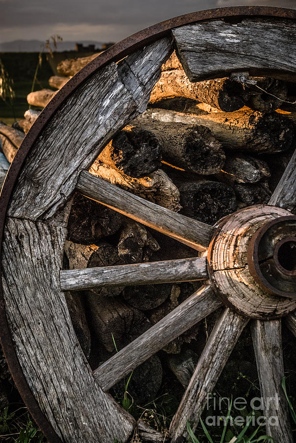 Sunset Photograph - Broken cart wheel with missing spoke and logs on a farm at Pacia by Peter Noyce