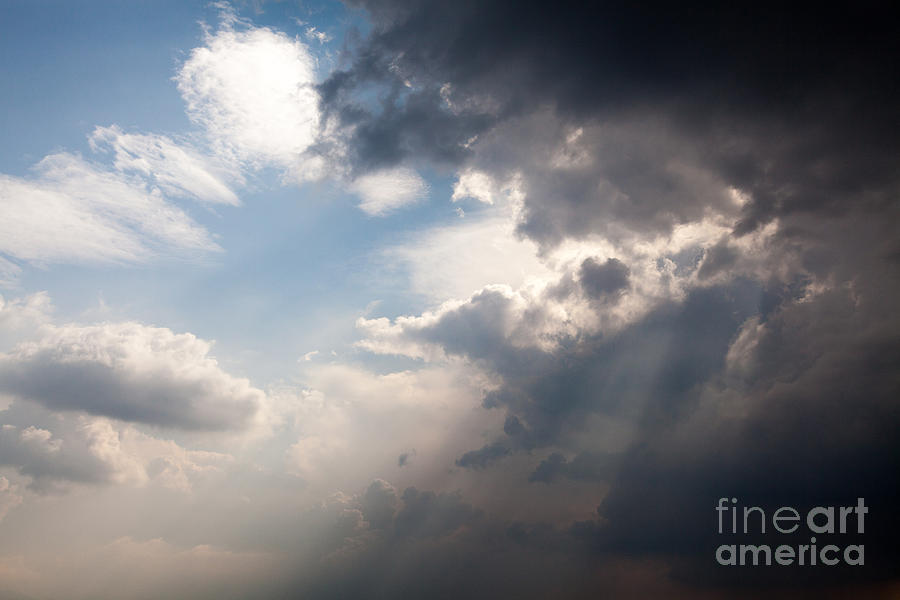 Broken rain clouds with blue sky and sun streaming through cloud Photograph by Peter Noyce