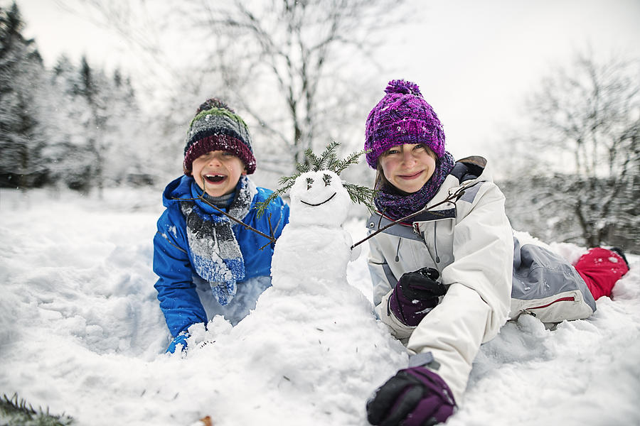 Brother and sister building snowmen on a winter day Photograph by Imgorthand