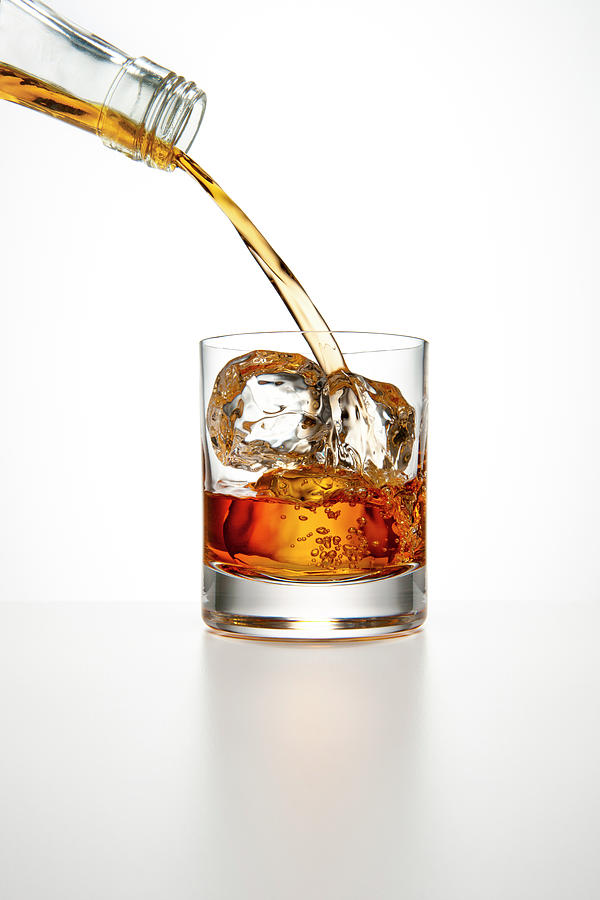 Brown Liquor Pouring Into A Glass Of Ice Photograph by Chris Stein