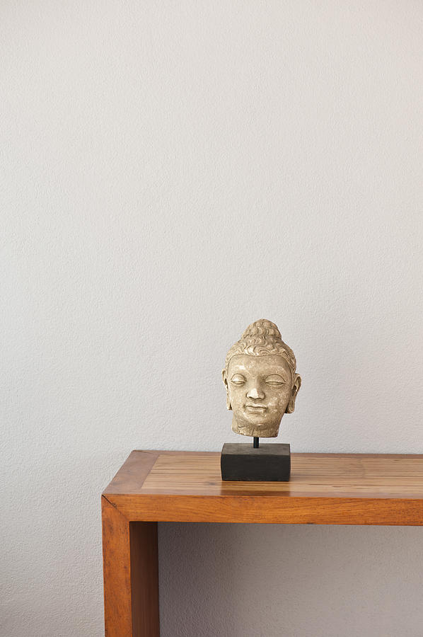 Buddha head in front of a grey wall Photograph by U Schade