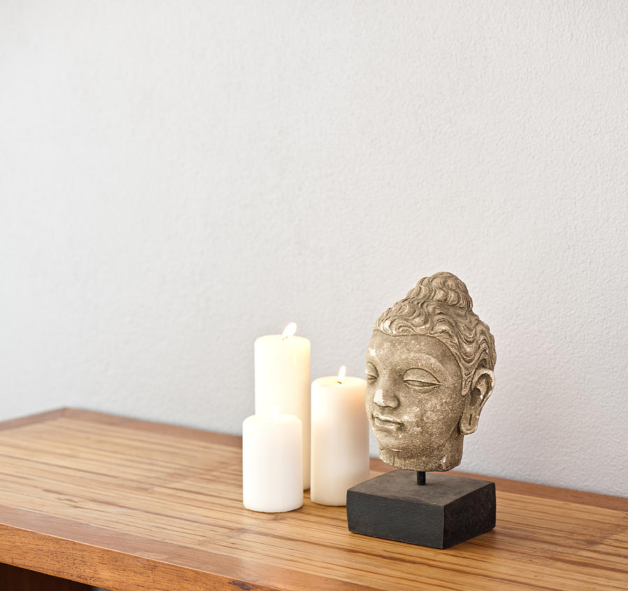 Buddha head with candles  Photograph by U Schade