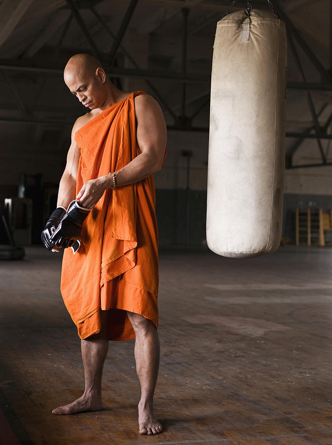 Buddhist monk wearing boxing glove in gym Photograph by Martin San