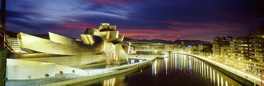 Sunset Photograph - Buildings Lit Up At Dusk, Guggenheim by Panoramic Images