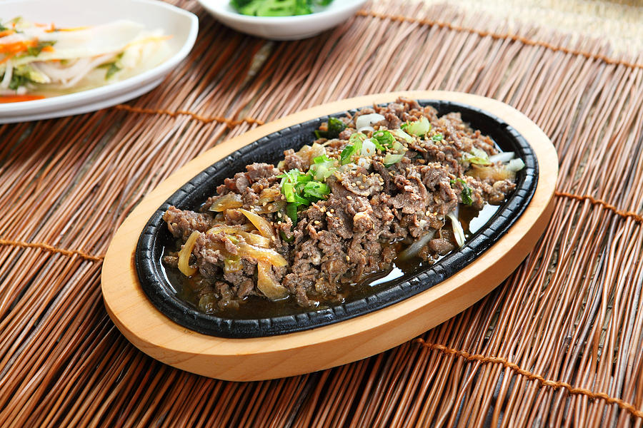 Bulgogi on a wooden platter on a straw table Photograph by Whitewish