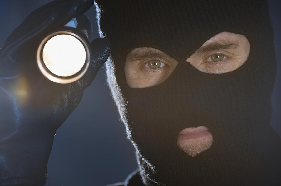 Burglar shining flashlight Photograph by Tetra Images