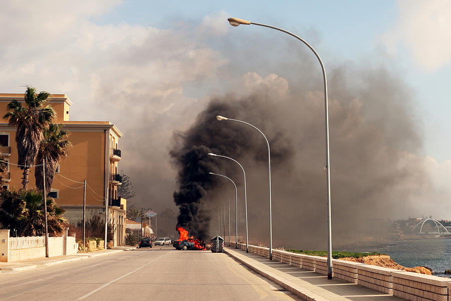Burning car in the street of sicilian town. Photograph by Peeterv
