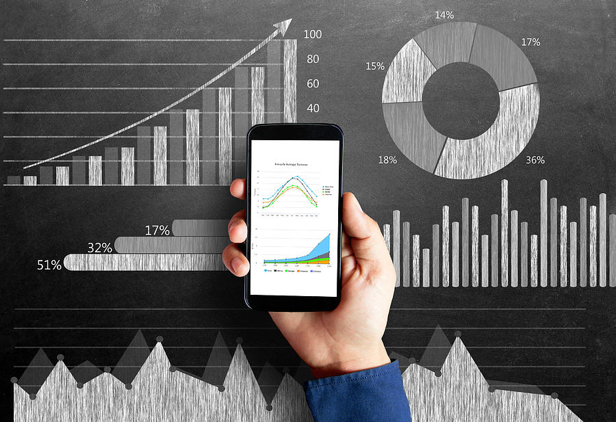 Business chart on blackboard with smart phone in human hand Photograph by Triloks