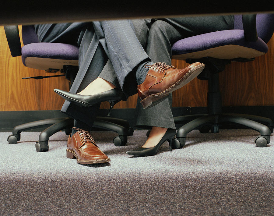 Business couple crossing legs under table, low section Photograph by Shannon Fagan
