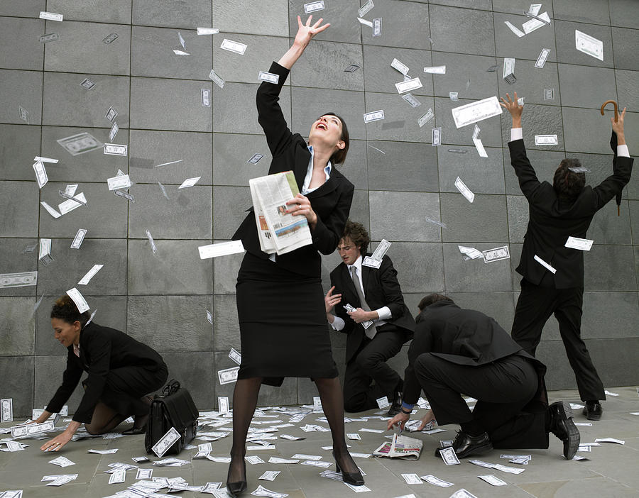 Business people on pavement catching falling money Photograph by Michael Blann