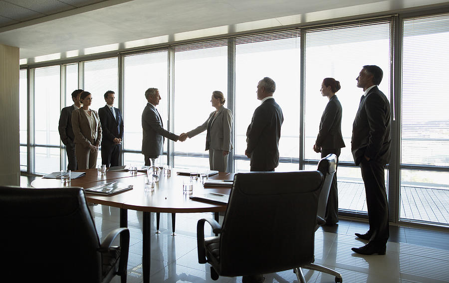 Business people shaking hands in conference room Photograph by Robert Daly