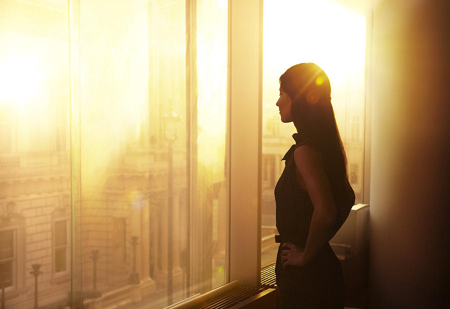 Business woman looking over the city at sunrise. Photograph by Ezra Bailey