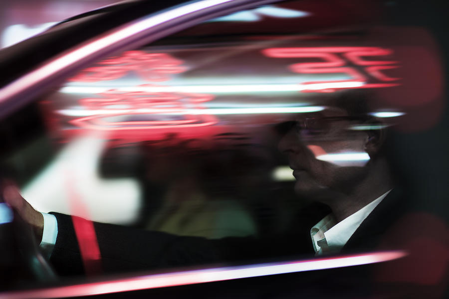 Businessman driving at night, illuminated and reflected lights on the car window Photograph by XiXinXing
