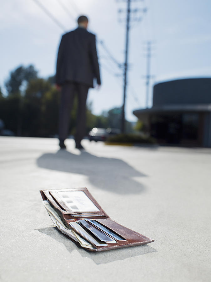 Businessman dropping wallet on sidewalk Photograph by Chris Ryan