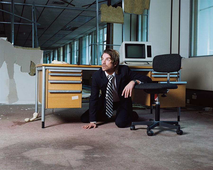 Businessman emerging from under desk Photograph by Image Source