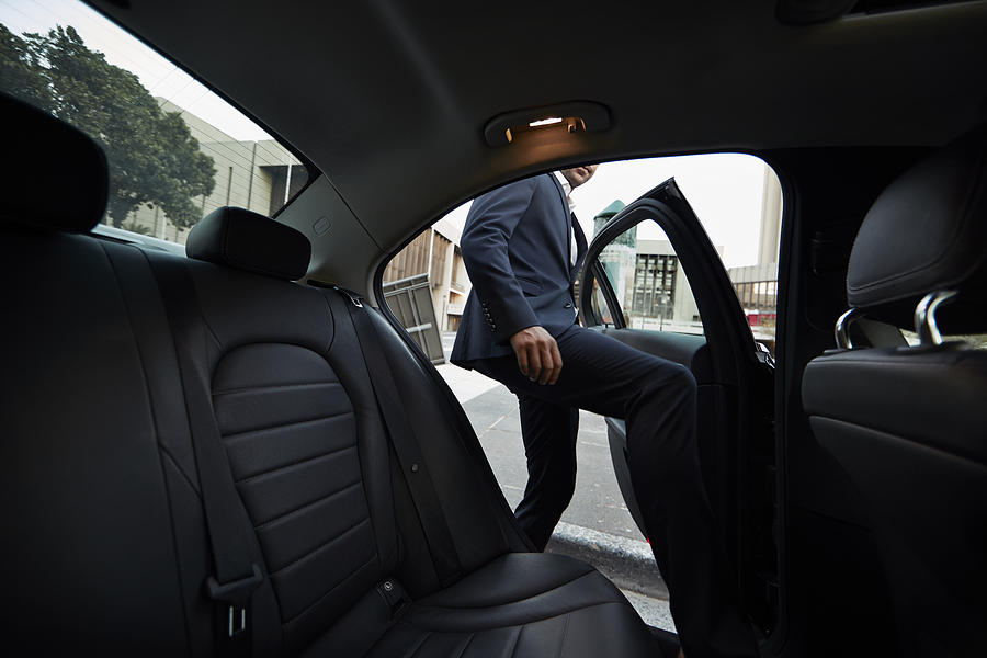 Businessman getting into backseat of exclusive cab Photograph by Klaus Vedfelt