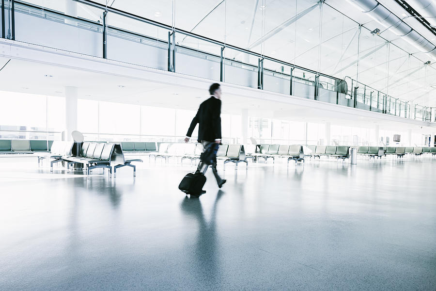 Businessman in a suit walks in airport terminal Photograph by Mlenny