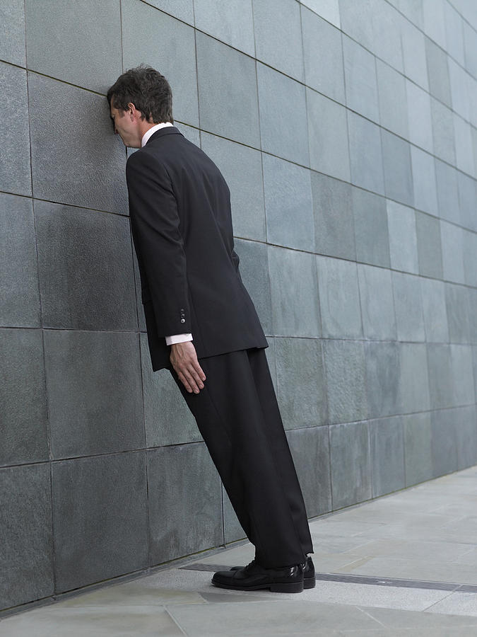 Businessman leaning forward, resting face against wall, side view Photograph by Michael Blann