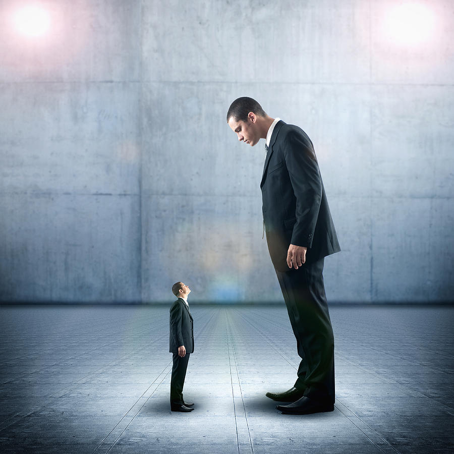 Businessman looking down on miniature colleague Photograph by Jacobs Stock Photography Ltd