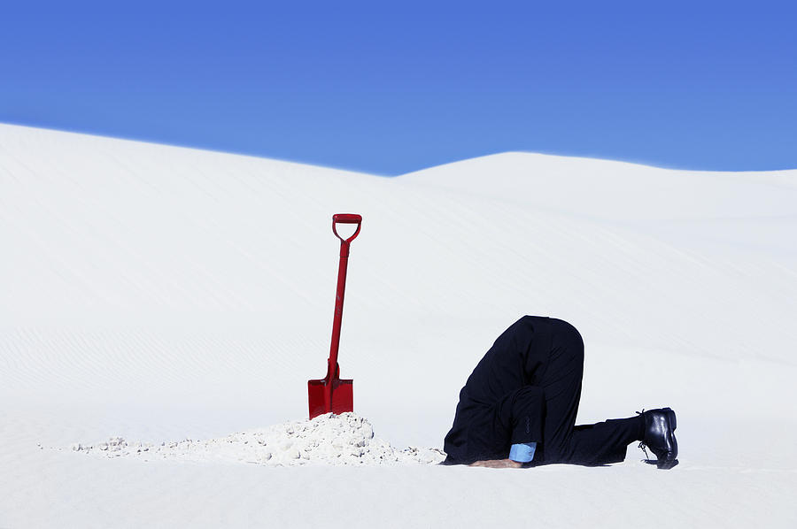 Businessman Next to a Spade Hiding His Head in a Hole in the Snow Photograph by John Cumming