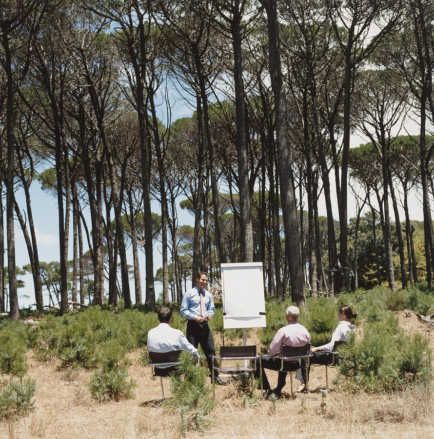 Businessman Presents to His Colleagues With a Flipchart in a Forest Photograph by Digital Vision.