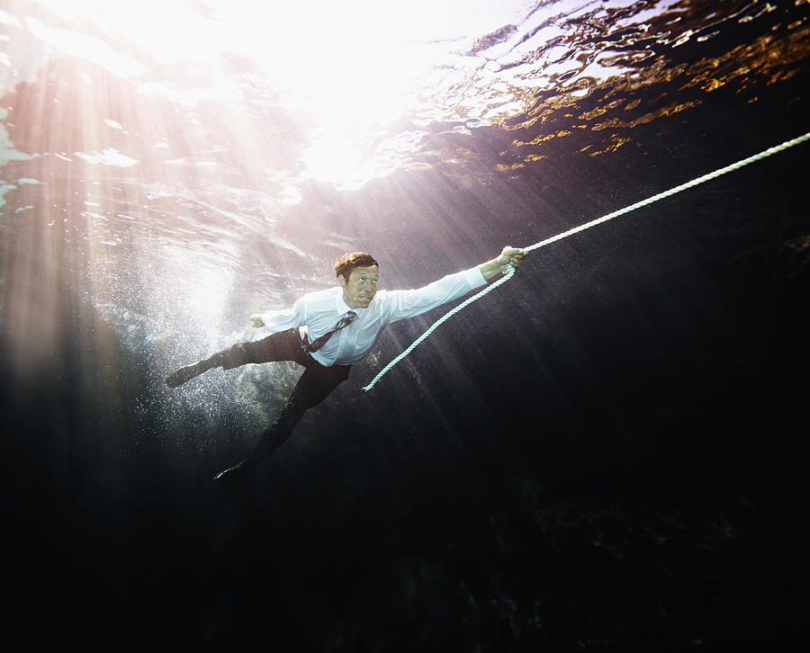 Businessman pulled by rope underwater Photograph by Thomas Barwick