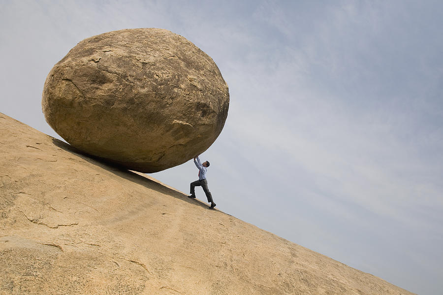 Businessman pushing large rock uphill Photograph by John M Lund Photography Inc