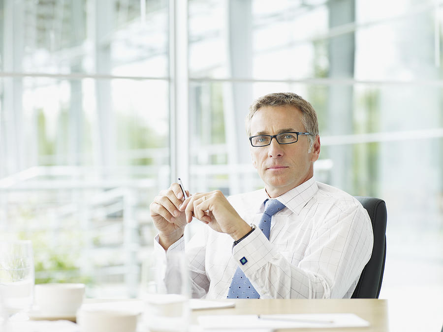 Businessman sitting at conference table Photograph by Chris  Ryan